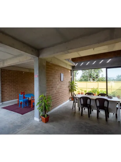 A dining and activity area at the Mathru Centre, with large sliding glass doors opening to a green patio, blurring the line between indoors and outdoors.