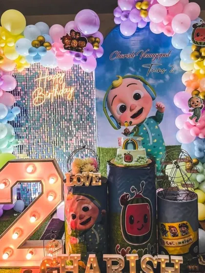 A grand Cocomelon party for Charish's second birthday, this setup includes a shimmering sequin wall, a large light-up number '2', and plenty of colorful balloons and characters.