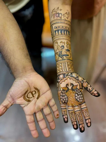 A close-up of the couple's mehendi, with the bride's intricate design and the groom's simple initial.