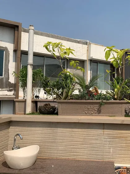 A view of a rooftop terrace project featuring large, built-in planters filled with a mix of ornamental and leafy green plants.