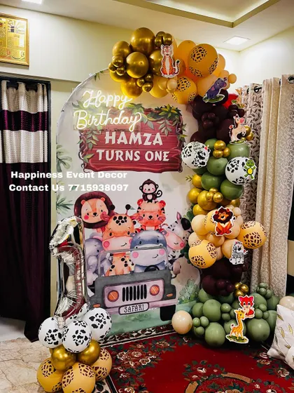 A closer view of the jungle safari first birthday decor, showing the detailed character illustrations on the backdrop and the mix of animal-print and solid-colored balloons.