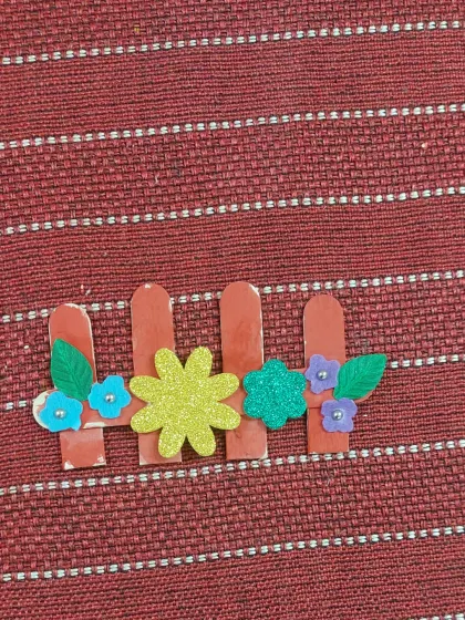 This simple but lovely garden fence was made using popsicle sticks and foam flowers. It's a great example of the simple, accessible crafts we do in our workshops.