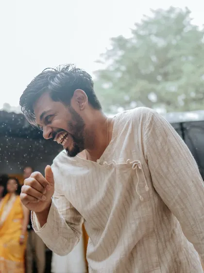 The groom shares a laugh, captured in a candid moment that reflects the joyful and relaxed atmosphere of the Haldi event.
