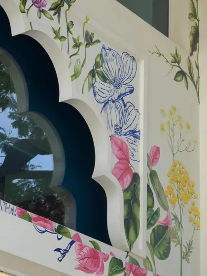 A close-up of the facade art, highlighting the intricate details of the flowers and the contrast between the painted sections and the line work. This piece is a portrait of Maharashtra's natural beauty.