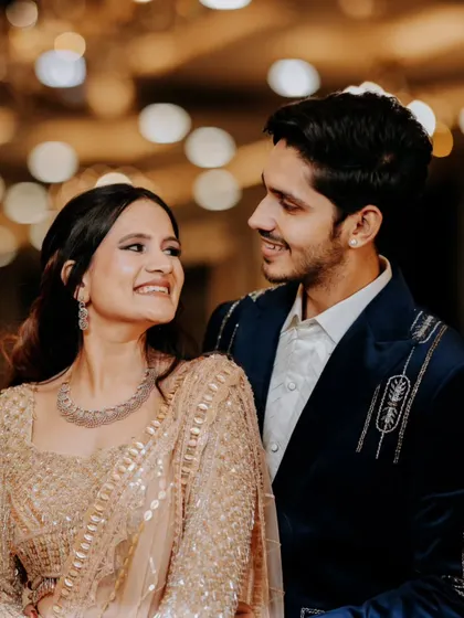 A sweet, candid moment between the couple at their reception, with beautiful bokeh from the background lights adding to the romantic atmosphere.