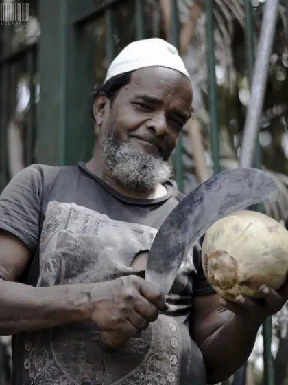 A different angle of the same coconut vendor, this time with a playful expression. It shows how I work with subjects on the street to capture different facets of their personality.