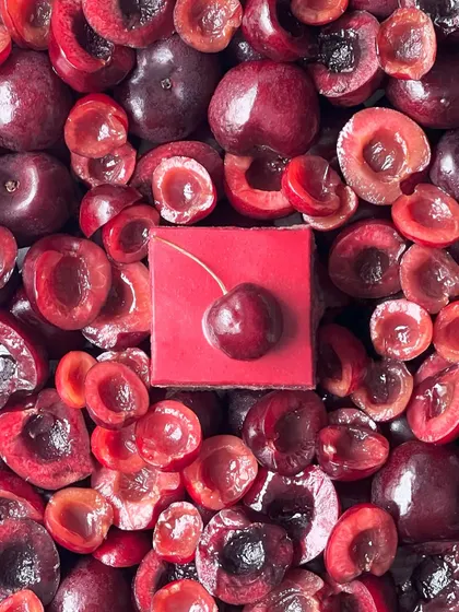A dramatic shot of the cherry opera gateau. The deep red of the fresh and halved cherries makes for a stunning photo and an even better dessert.