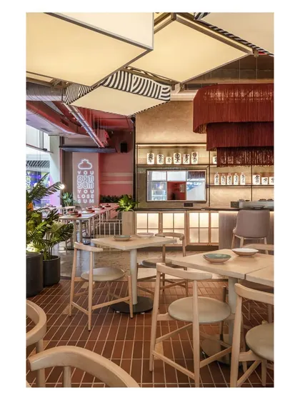 This perspective shows the harmony between different lighting sources, from the large patterned lanterns to the dramatic red tassel chandelier and the soft glow of the bar. Each light source is chosen to define a zone and contribute to the overall mood.