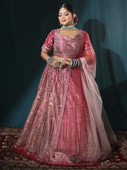This pink bridal lehenga is adorned with intricate threadwork and sequins. It’s a beautiful option for either the wedding or the reception.