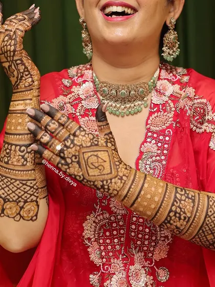 The back of the hands is just as important as the front. Here is a happy bride showing off her detailed back-hand mehendi, featuring a personalized initial monogram and beautiful floral and geometric patterns.