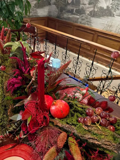 A detailed shot of the table runner, showing how fruits like pomegranates and grapes are woven into the moss and floral design.