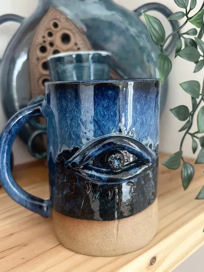 This striking evil eye mug was hand-built in a workshop. The deep blue glaze makes the design pop.