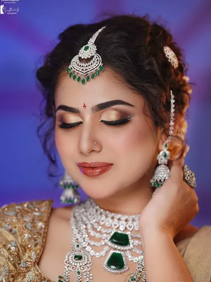 A close-up of a glamorous reception look with diamond and emerald jewelry. The golden cut-crease eyeshadow is a technique my students master.