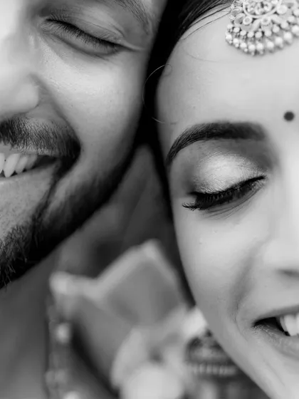 A close-up black and white shot focusing on the couple's joyful smiles and the bride's beautiful eye makeup.