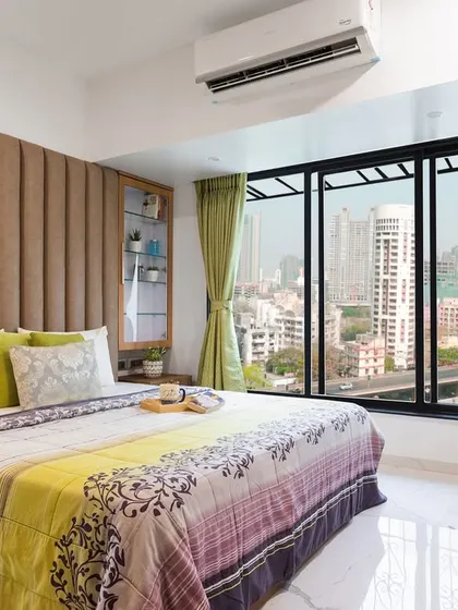 This home isn't just designed, it's curated. A perfect play of colors, with a cozy bedroom featuring a plush headboard and a stunning city view.