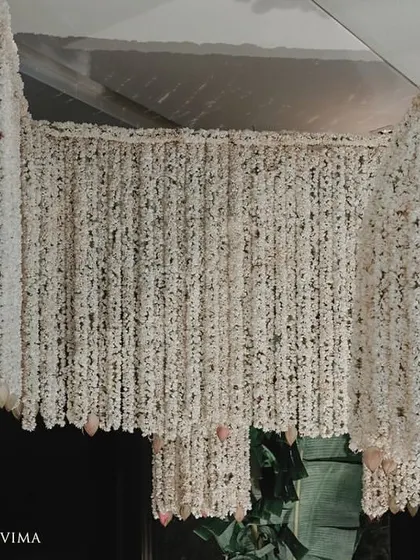 The entrance to a half-saree ceremony, adorned with fragrant jasmine garlands and banana leaves. The reflection on the polished floor doubles the beauty of this traditional South Indian decor.