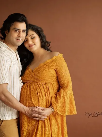 A warm and earthy studio portrait. The brown backdrop and the couple's relaxed pose create a feeling of comfort, intimacy, and grounded love.