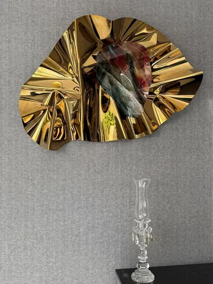 The golden sculpture's radial folds create a sunburst effect, adding warmth and luxury to the bar area.