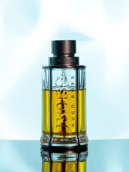 This is a clean and fresh take on a standard product shot. The cool blue, soft-focus background gives a sense of freshness, while the sharp focus on the bottle and its reflection maintains a professional, high-quality feel suitable for websites and digital ads.