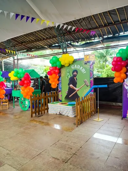 A full view of the game booth area at a Punjabi-themed party, featuring a hammer game and a tattoo station.