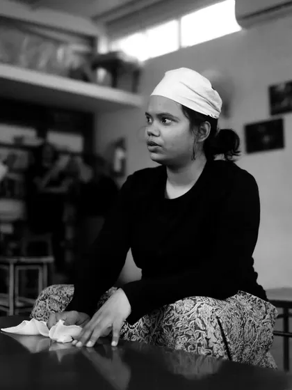 An actor cleans a table, fully in character during a rehearsal scene.