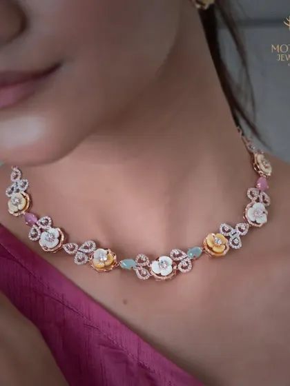A whimsical and romantic necklace featuring floral motifs made of mother-of-pearl and accented with colorful gemstones. It is a unique piece that tells a story of a garden in bloom.