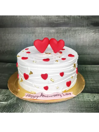 A simple yet beautiful chocolate truffle cake for an anniversary. The rustic finish is decorated with gold leaf and fondant hearts.