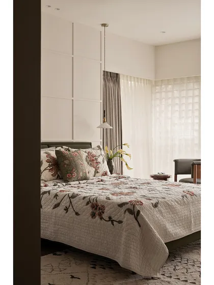 This guest bedroom from "Apartment 222" combines rest and reflection. The floral bedspread adds a touch of traditional charm, while the clean lines of the wall paneling and bedside table keep the space feeling modern and uncluttered.