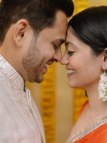 An intimate close-up of the couple, their foreheads touching, capturing a quiet moment of connection amidst the wedding festivities.
