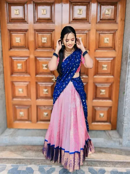 A standing pose of a client in the pink and blue half saree, showing how the outfit looks in its entirety.