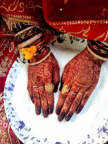 A closer look at the bride's hands during her Nikkah ceremony, showing the beautiful contrast of the dark mehendi and gold rings.