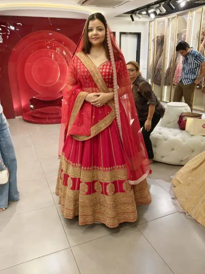 This happy client is glowing in a classic red and gold bridal lehenga. The traditional design with a broad embroidered border makes it a timeless choice for any bride.