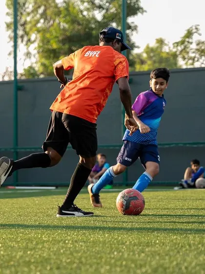 A coach demonstrates a skill to a young player, providing one-on-one guidance.