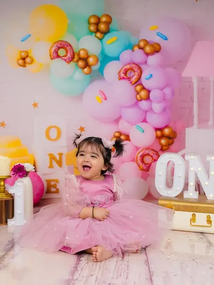 The pure, uncontainable joy of turning one. This little princess is surrounded by a pastel wonderland of donuts and ice cream props.
