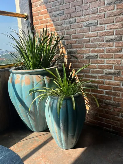 We love the rustic charm of these large, weathered-finish turquoise planters. They add a beautiful, aged look to this sunny balcony with a brick wall backdrop.