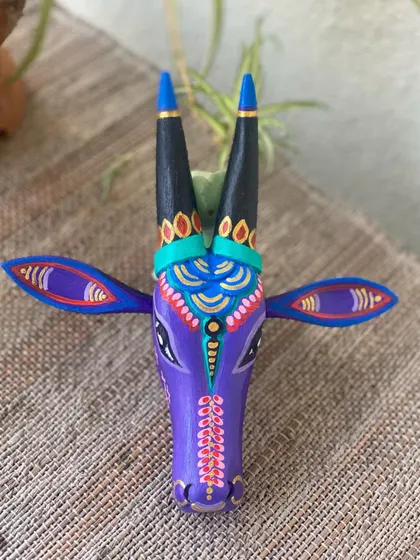 A frontal view of the purple Nandi, highlighting the symmetry of the patterns and the playful combination of colors.