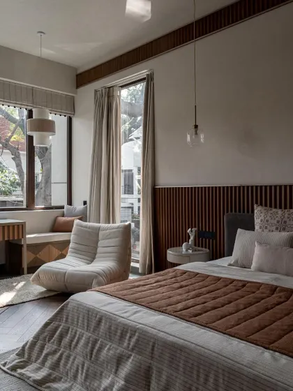A bedroom in the Pràna house with a large window and a cozy built-in daybed. This is a perfect example of a multi-functional bedroom design, offering spaces for sleep, work, and relaxation.
