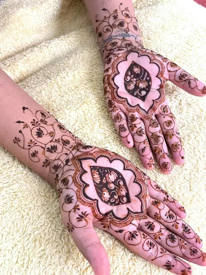 Another angle of the unique bridal henna, showing both hands and the complementary vine work on the arms.
