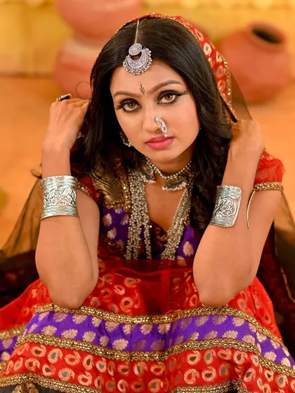 A full-body shot of the Rajasthani folk look. The rustic setting with clay pots and a simple tree branch enhances the traditional, earthy feel of the concept.