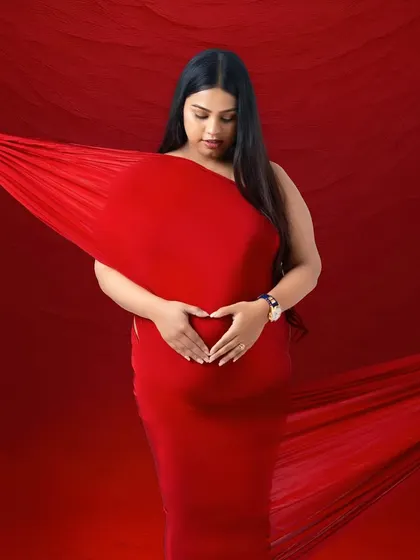 Making a heart shape over the baby bump is such a sweet gesture. The rich red fabric creates a powerful and loving image.