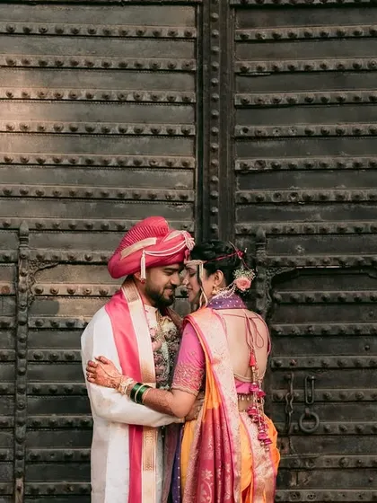 The couple shares an intimate moment against the backdrop of a grand, traditional Indian door.