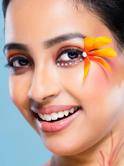 A joyful beauty portrait with a creative, Hawaiian-inspired theme, featuring orange floral makeup accents and a bright smile. This shows my ability to execute fun, thematic beauty concepts.