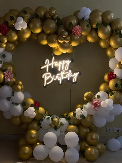 The heart-shaped birthday balloon setup shown in a darker ambiance to emphasize the neon sign.