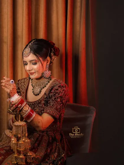 A classic bridal portrait showing the bride adjusting her kaleeras. These traditional moments are an essential part of the wedding album.