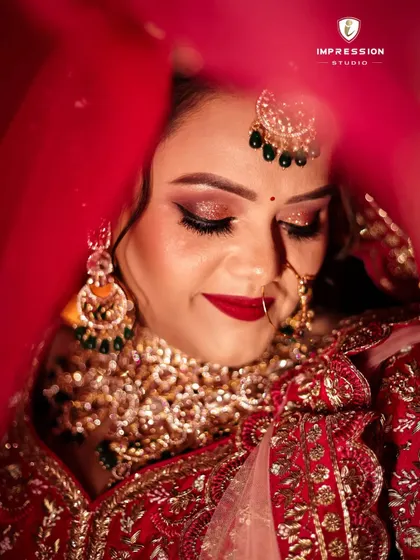 A close-up of the bride, her eyes closed, with the red veil creating a beautiful, soft frame around her face.
