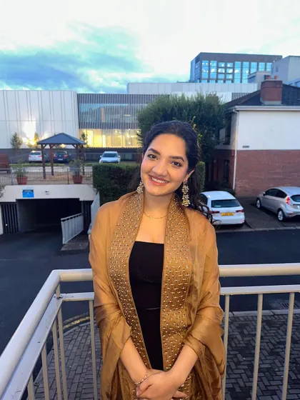 A smiling portrait of the client in her gold chiffon cape. It's a lightweight yet impactful piece, perfect for adding a touch of festive elegance to a simple base.