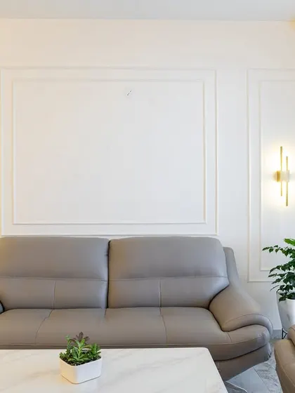 A close-up of the elegant wall molding and modern brass wall sconces. These details add a layer of sophistication and architectural interest to the living room.