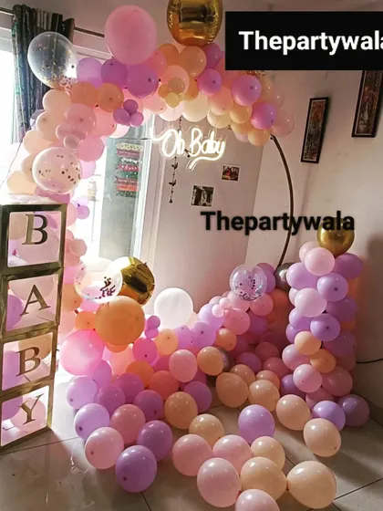 A fun and playful baby shower setup with a cascade of pastel balloons and 'BABY' blocks.