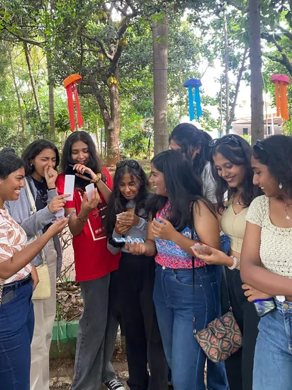 A large group of friends gathered around, comparing their photo strips and sharing a laugh.
