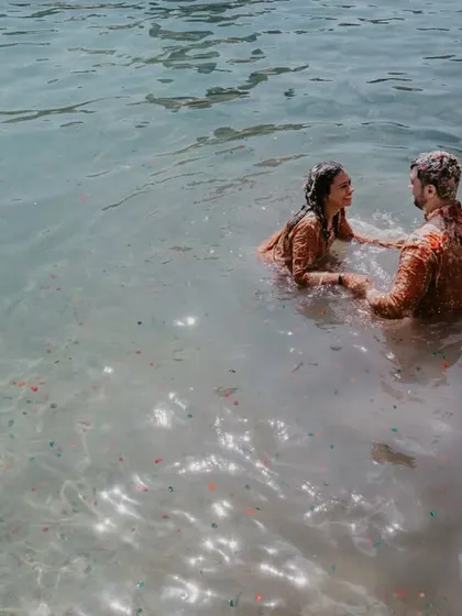 The ultimate post-haldi cool down. This shot captures the couple taking a spontaneous dip in the ocean, a perfect end to their celebration.